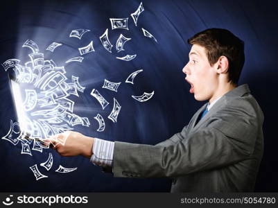 E-business concept. Young businessman looking shocked in laptop monitor