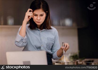 E-Learning Concept. Young Woman Try to Practice and Learn for Cooking at Home via the Internet