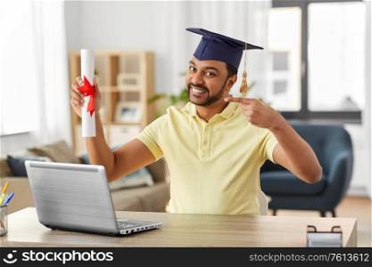 e-learning, education and people concept - happy smiling indian male graduate student with laptop computer and diploma at home. indian student with laptop and diploma at home