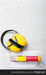 Ear hearing protection. Yellow working protective headphones noise muffs, and notched trowel, toolwork in construction site