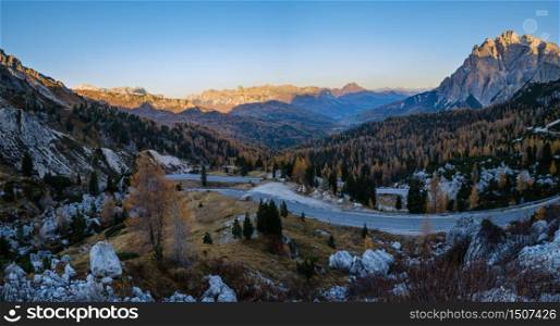 Early morning autumn alpine Dolomites mountain in first sunrays. Peaceful panoramic view from Valparola Pass, Belluno, Italy. Picturesque traveling, seasonal, and nature beauty concept scene.
