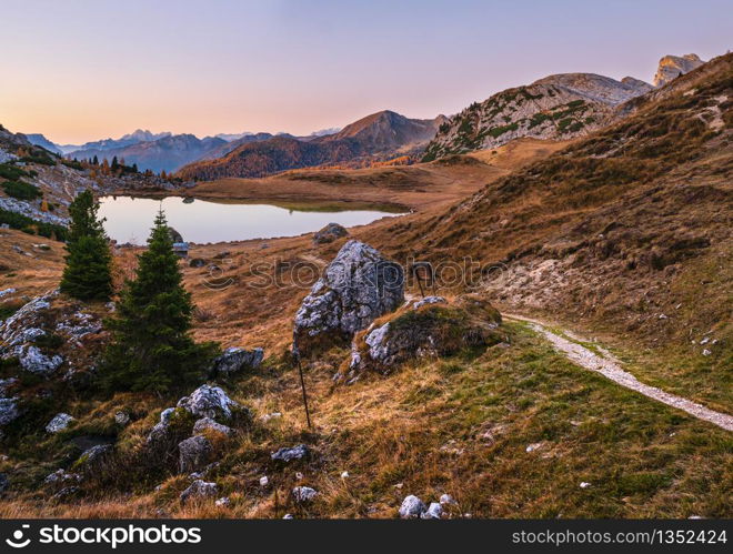 Early morning autumn alpine Dolomites mountain scene. Peaceful Valparola Pass and Lake view, Belluno, Italy. Picturesque traveling, seasonal, and nature beauty concept scene.