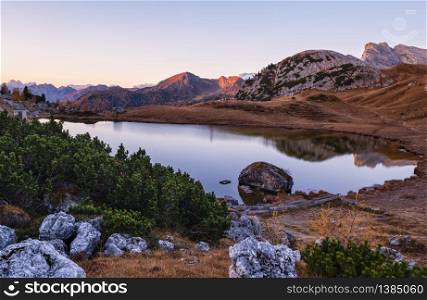 Early morning autumn alpine Dolomites mountain scene. Peaceful Valparola Pass and Lake view, Belluno, Italy. Picturesque traveling, seasonal, and nature beauty concept scene.