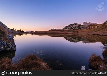 Early morning autumn alpine Dolomites mountain scene. Peaceful Valparola Path and Lake view, Belluno, Italy. Picturesque traveling, seasonal, and nature beauty concept scene.