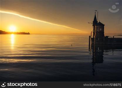 Early morning on the lake Constance and a small lighthouse. Sunrise reflected in water lake in Konstanz, Germany. Relaxing landscape.