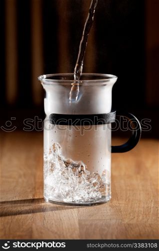 Early morning tea - glass being filled with water with strong directional light