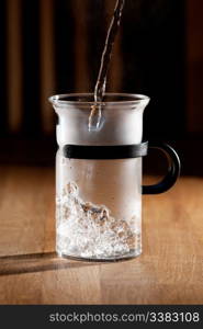 Early morning tea - glass being filled with water with strong directional light