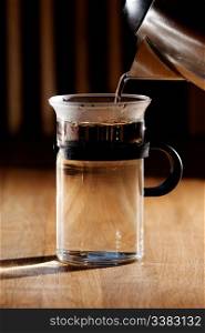Early morning tea - glass being filled with water with strong directional morning light