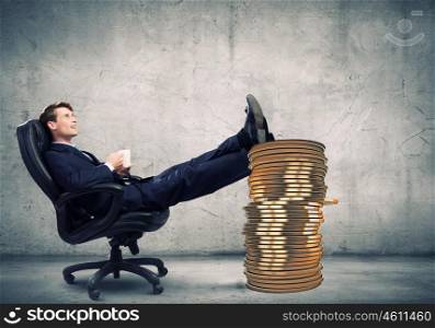 Earning money. Young confident businessman sitting in chair with legs on cent coin