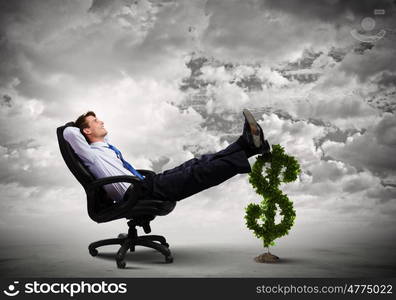 Earning money. Young confident businessman sitting in chair with legs on dollar sign