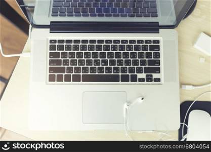earphone and laptop computer notebook on wooden table, vintage tone