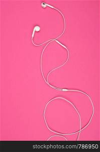 earphones with a white cable on a pink background, abstract backdrop