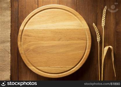 ears of wheat and cutting board on wooden background