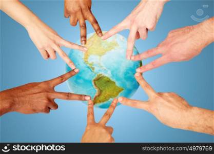 earth day, diversity, ethnicity, international people concept - group of hands showing peace hand sign over blue background and planet. group of international people showing peace sign
