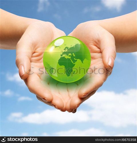 earth day, people, ecology and environment concept - close up of female hands holding green globe over blue sky and clouds background. close up of female hands holding green globe. close up of female hands holding green globe