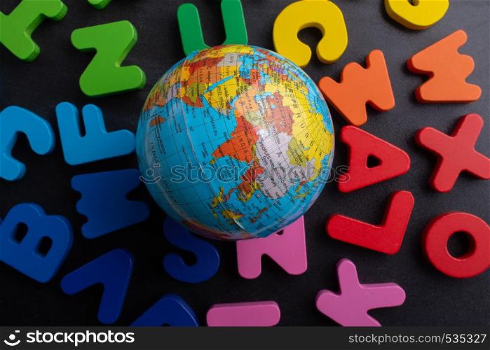 Earth globe model on colorful letters on a black background