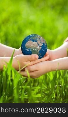 Earth in children`s hands against green spring background. Elements of this image furnished by NASA