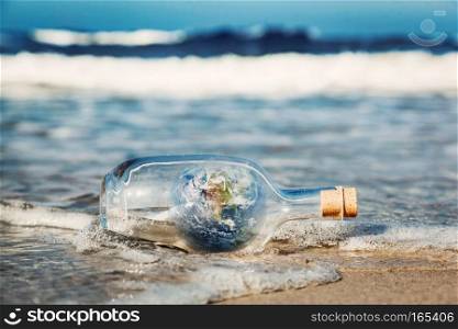 Earth in the bottle coming with wave from ocean. Concept of environment, nature care, save clean world message. Elements of this image furnished by NASA. Earth in the bottle coming with wave from ocean. Environment, clean world message