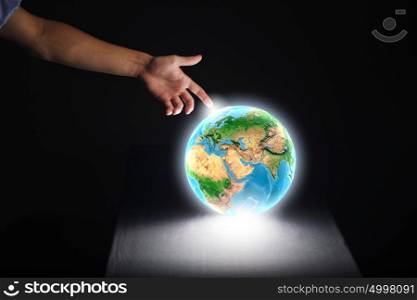 Earth planet. Close up of human hand touching Earth planet with finger. Elements of this image are furnished by NASA