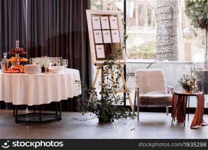 easel with wooden Stylish Board list seating plan for wedding reception. Vintage luxury wedding. table with fruit and champagne for guests.. easel with wooden Stylish Board list seating plan for wedding reception. Vintage luxury wedding. table with fruit and champagne for guests