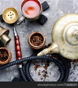 East smoking hookah. Arabian shisha with tea. Hookah and tea.. Modern hookah with tea