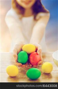 easter and holiday tradition concept - close up of happy girl holding colored eggs over sky background. close up of girl holding colored easter eggs