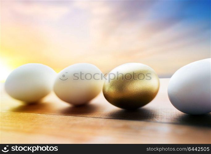 easter and object concept - close up of golden and white eggs on wood over sky background. close up of golden and white easter eggs on wood