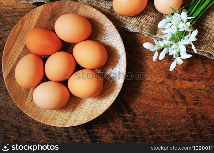 Easter background. Rustic wooden table with plate, egg, flowers and cutting board . Top view. Copy space.. Easter background. Rustic wooden table with plate, egg, flowers and cutting board . Top view.