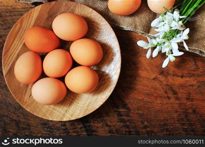 Easter background. Rustic wooden table with plate, egg, flowers and cutting board . Top view. Copy space.. Easter background. Rustic wooden table with plate, egg, flowers and cutting board . Top view.