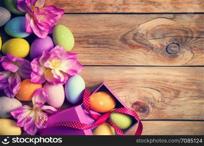 Easter background with Easter eggs and flower on wooden table. Top view. Copy space