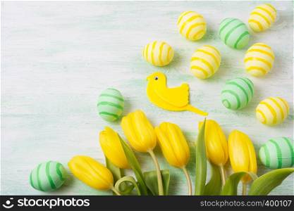 Easter background with green and yellow striped painted eggs, tulips and bird. Happy Easter greeting card, copy space.