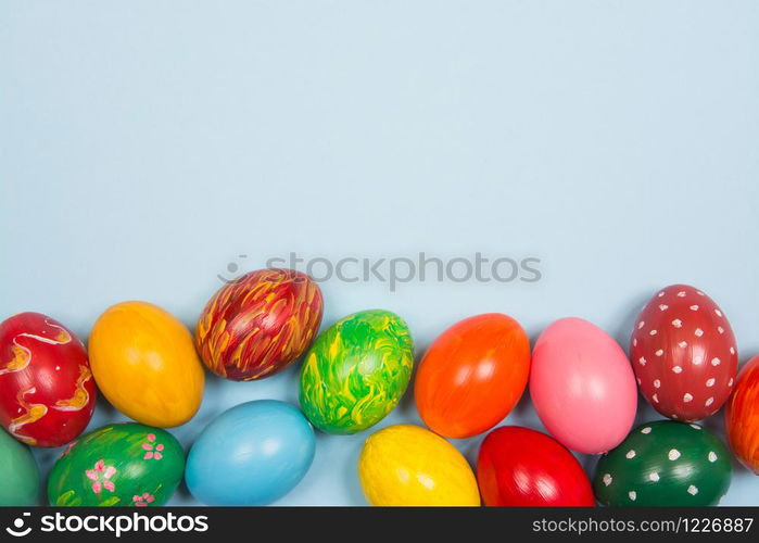 Easter background with handmade colored eggs on wooden a bright blue background. Frame and copy space.