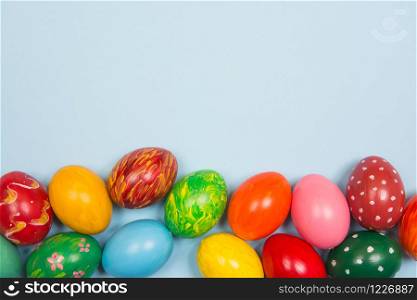 Easter background with handmade colored eggs on wooden a bright blue background. Frame and copy space.