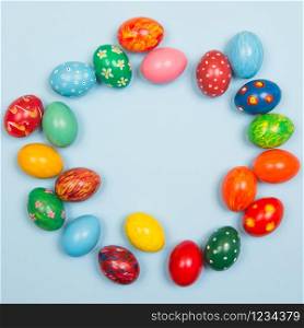Easter background with handmade colored eggs on wooden a bright blue background. Frame and copy space.