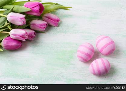 Easter background with pale pink striped painted eggs and white pink tulips. Happy Easter greeting card, copy space.