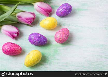 Easter background with white, pink, purple, yellow glitter and stars decorated eggs and tulips. Happy Easter greeting card, copy space.