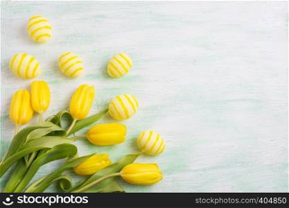 Easter background with yellow striped painted eggs and tulips. Happy Easter greeting card, copy space.