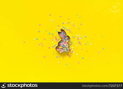 Easter Bunny shape form and scattering multicolored confectionery topping dressing on yellow paper. Concept Easter festive background. Copy space, Top view.. Easter Bunny shape form and scattering multicolored confectionery topping dressing on yellow paper. Concept Easter festive background. Copy space, Top view