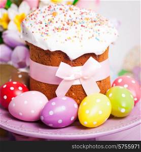 Easter cake and colorful polka dot eggs on the plate and flowers on the foreground. Easter cake