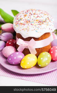 Easter cake and colorful polka dot eggs on the plate and flowers on the foreground. Easter cake