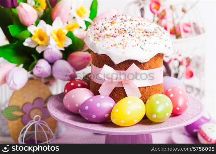 Easter cake and colorful polka dot eggs on the plate and flowers on the foreground. Easter cake
