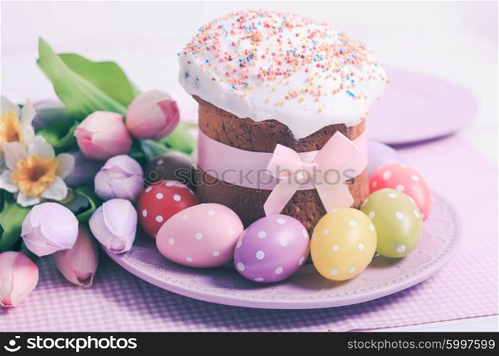 Easter cake and colorful polka dot eggs on the plate and flowers on the foreground. The Easter cake