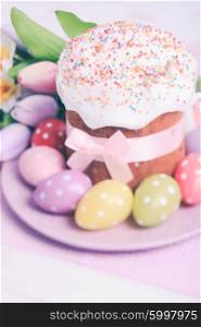 Easter cake and colorful polka dot eggs on the plate and flowers on the foreground. The Easter cake
