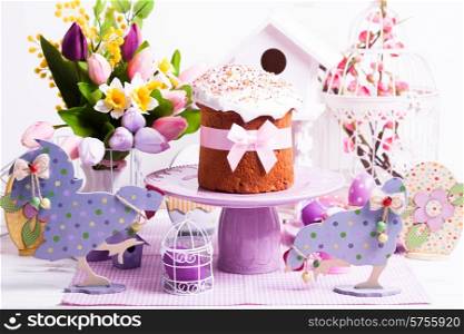 Easter cake and lilac desorations - wooden chicken and cock on the foreground. Easter cake