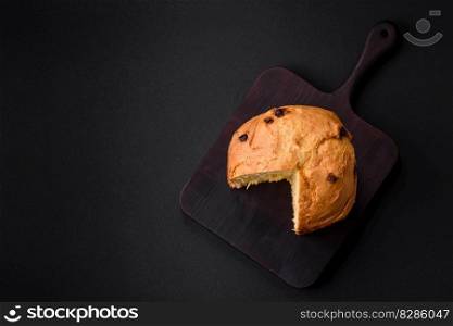 Easter cake or panettone with raisins and candied fruits on a dark concrete background