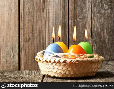 Easter candles in egg form on old wooden table