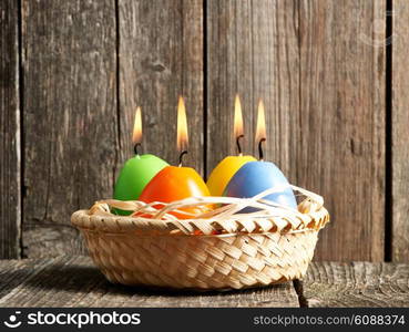 Easter candles in egg form on old wooden table