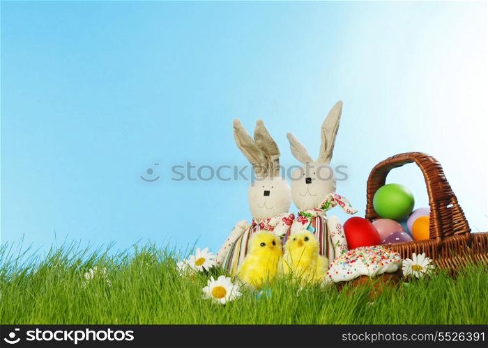 Easter card with eggs in basket and toy rabbits on green grass