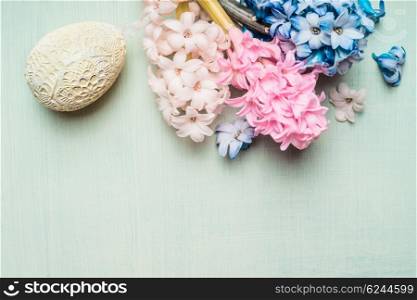 Easter card with hyacinths flowers and decor egg on light green background, top view.
