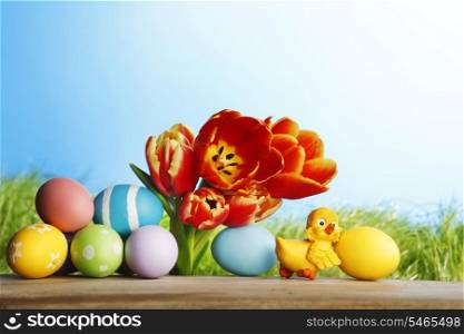 Easter card with little chick, colorful painted eggs and tulips